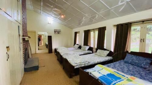 a room with three beds and a couch and windows at Bilour House Main Dunga Gali Bazar, nathiagali in Dunga Gali