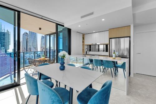 an open kitchen and dining room with a white table and blue chairs at The Gallery Residences Broadbeach - Official Listing in Gold Coast