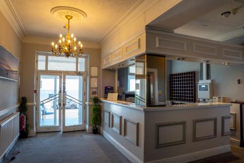 a kitchen with a large island with a chandelier at The Seafront Hotel by Compass Hospitality in Llandudno