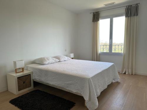 une chambre blanche avec un lit et une fenêtre dans l'établissement Belle villa climatisée avec piscine, à Tornac