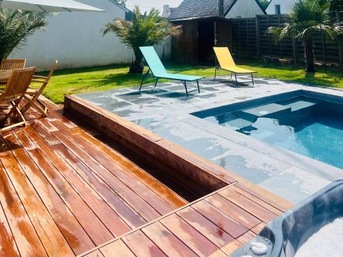 - deux chaises assises sur une terrasse à côté d'une piscine dans l'établissement Villa Leonic - Piscine et Jacuzzi, à La Forêt-Fouesnant