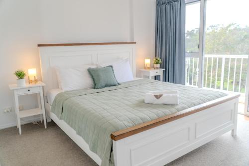 a bedroom with a large white bed with two night stands at Fairways Golf & Beach Retreat Bribie Island in Woorim