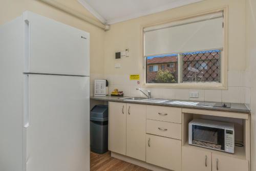 a kitchen with a refrigerator and a sink and a window at Caboolture Central Motor Inn, Sure Stay Collection by BW in Caboolture