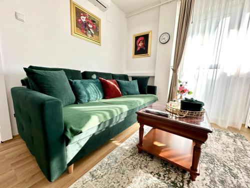 a green couch in a living room with a table at Studio PANORAMIC with Balcony and Parcul Unirii view in Alba Iulia