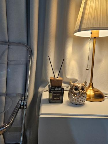 a table with a lamp and a clock on it at 스칼렛 스테이 수원역 - Scarlett Stay at Suwon Station in Suwon