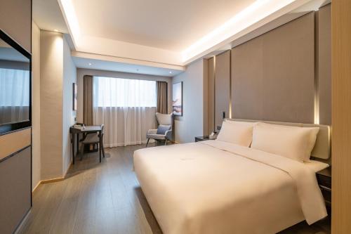 a bedroom with a large white bed and a desk at Atour Hotel Shenzhen Luohu Vientiane City in Shenzhen