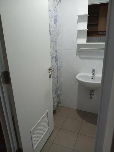 a white bathroom with a sink and a mirror at Skylounge Makassar Apartment in Manda