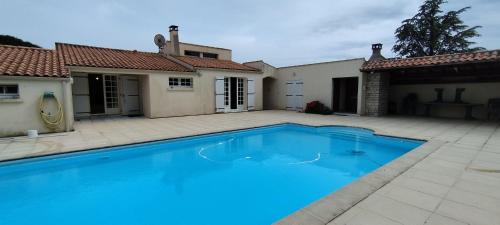 une grande piscine bleue devant une maison dans l'établissement Maison familiale avec piscine près de la plage de Foulerot, à Saint-Georges-dʼOléron