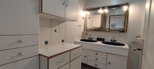 une salle de bain blanche avec deux lavabos et un miroir dans l'établissement Maison familiale avec piscine près de la plage de Foulerot, à Saint-Georges-dʼOléron