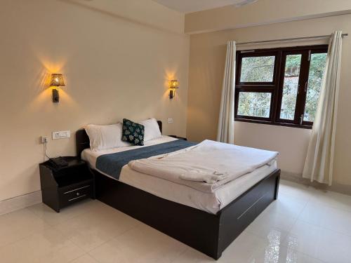a bedroom with a large bed with a window at Hotel Cymbidium Residency in Tādong