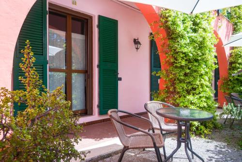 a table and chairs outside of a house with green shutters at Villa Gaia in Portoferraio