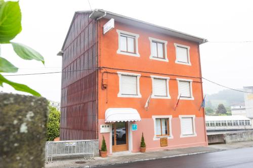a orange building with white windows on a street at Pension O Remo in O Vicedo