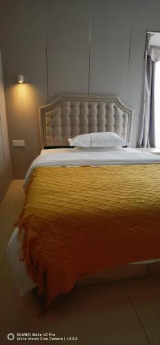 a bed with a yellow blanket and a window at YuMi Gaopai in Guangzhou