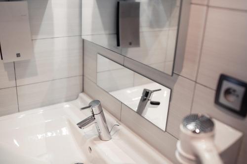 a bathroom with a sink and a mirror at Hôtel le Grillon in Strasbourg