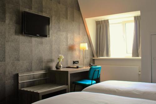 a hotel room with a bed and a desk and a television at Het Wapen van Harmelen in Harmelen