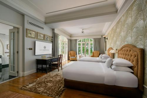 a large bedroom with two beds and a desk at Eastern & Oriental Hotel in George Town