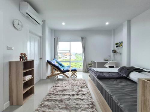 a bedroom with a bed and a chair and a window at Hidden Gems Residence in Ban Sala Daeng