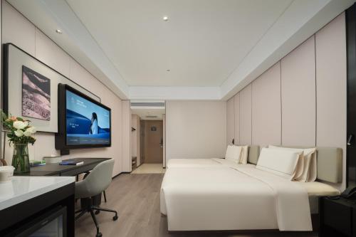 a bedroom with a bed and a desk and a tv at Atour X Hotel Changchun Zoological and Botanical Gardens Freedom Avenue in Changchun