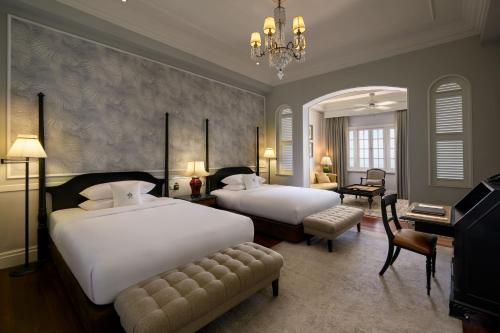a hotel room with two beds and a chandelier at Eastern & Oriental Hotel in George Town