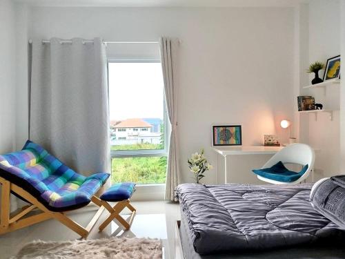 a bedroom with a bed and a chair and a window at Hidden Gems Residence in Ban Sala Daeng