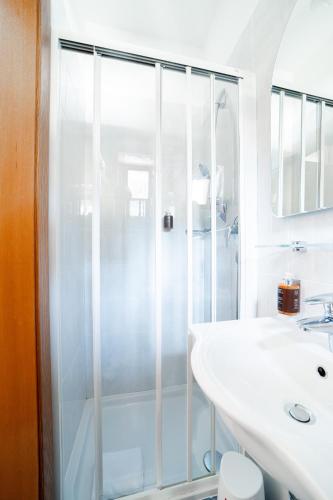 a white bathroom with a shower and a sink at Hotel Euròpa Dolomites in Selva di Val Gardena