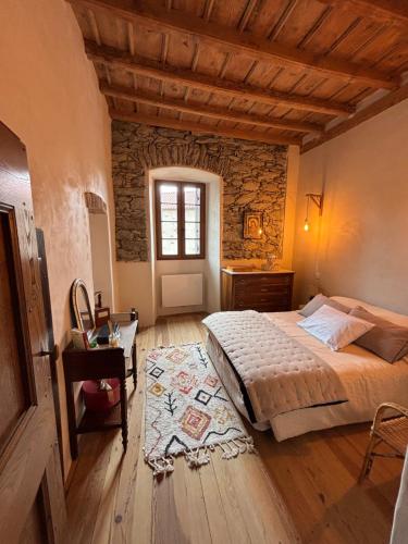 une chambre avec un lit, une table et une fenêtre dans l'établissement Maison de Caractère au coeur du village, à Castifao