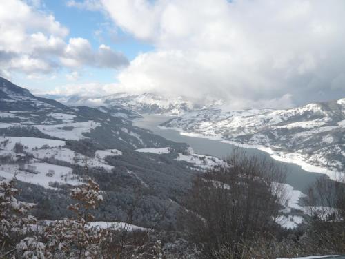 a view of a snowy mountain range with a lake at Hôtel Bel'Air in Jausiers