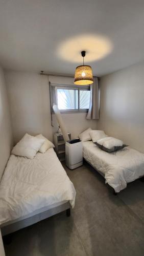 deux lits dans une chambre avec une fenêtre dans l'établissement Marina Sète, à Sète