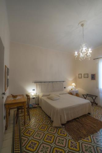 a bedroom with a bed and a chandelier at S'Attobiu Guest Rooms in Teulada