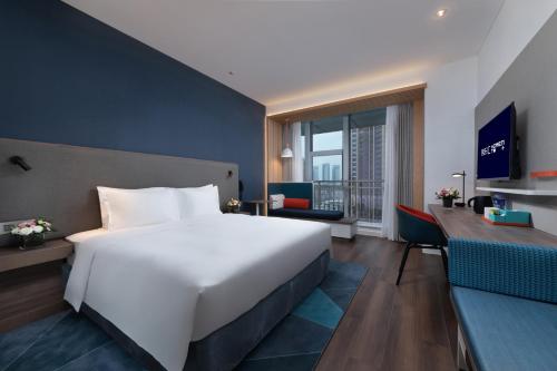 東莞市にあるCNHOL RADIENT HOTEL Dongguan Humenの大きな白いベッドと机があるホテルの部屋