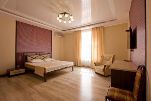 a bedroom with a bed and a chair and a window at Center Hotel in Bishkek