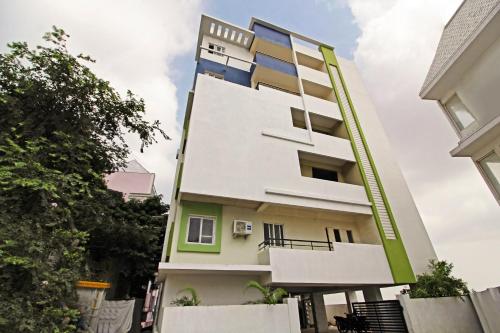 un edificio alto de color blanco con toques verdes en Hotel O HILL 9, en Hyderabad