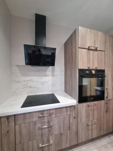 une cuisine avec des armoires en bois et un micro-ondes noir dans l'établissement Appartement Cosy 3 chambres - Proche de Paris, à Arcueil