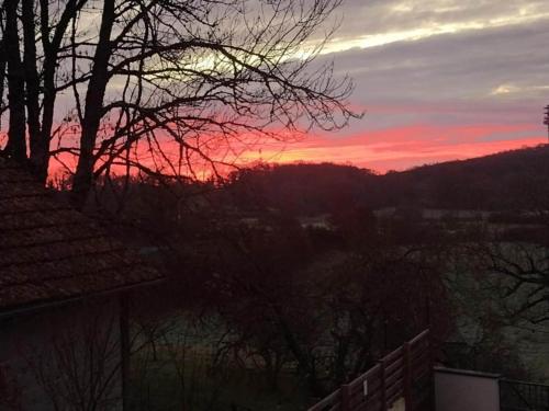 a sunset over a city with trees in the foreground at Slate-Roofed Hideaway in Cressensac
