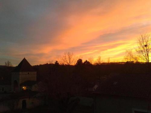 a sunset over a city with trees and a building at Slate-Roofed Hideaway in Cressensac