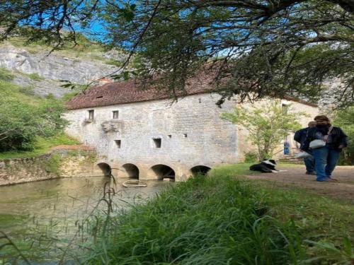 a man walking past a stone building next to a river at Slate-Roofed Hideaway in Cressensac