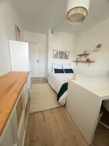 une chambre blanche avec un lit et un bureau dans l'établissement Appartement 6 chambres, au Mans