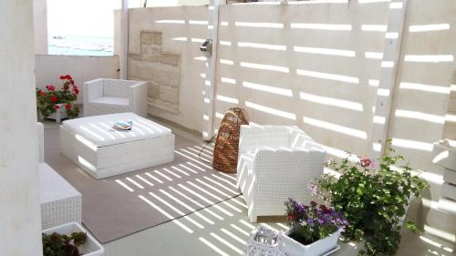 a living room with white furniture and some plants at Appartamenti e Camere Silva Trapani in Trapani