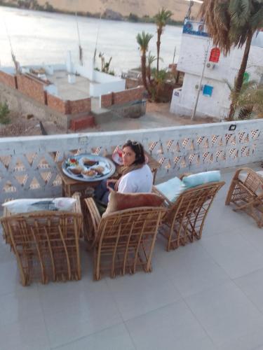 a woman sitting on a balcony with a plate of food at Nubian Life Nile View in Aswan