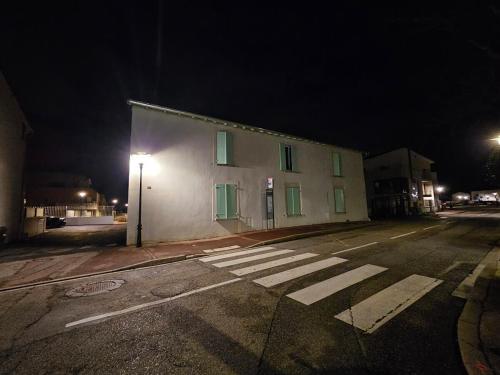 a white building with green windows on a street at night at Le Loft de Genas - la Bastide, le Chalet, le Loft, le Mas, la Paillote in Genas