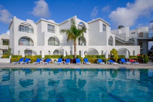 a large white building with blue chairs and a swimming pool at Pandream Hotel Apartments in Paphos