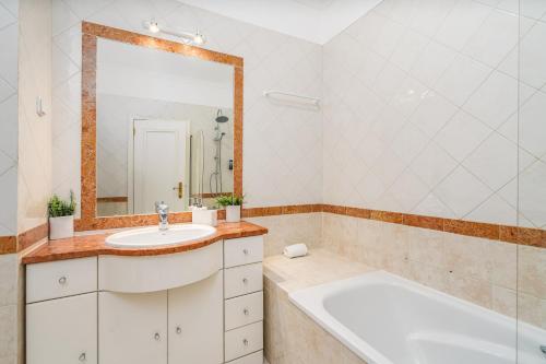 a bathroom with a tub and a sink and a mirror at Vilamoura Central 2 Bedroom Flat in Vilamoura