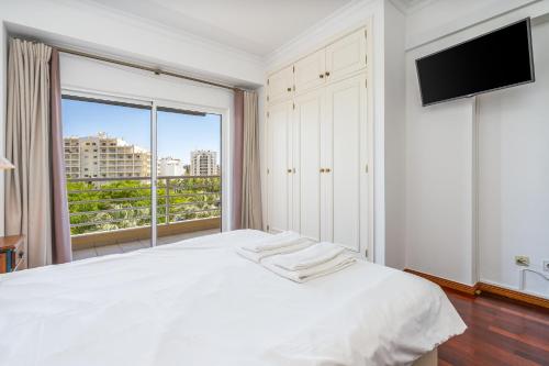a bedroom with a white bed and a large window at Vilamoura Central 2 Bedroom Flat in Vilamoura