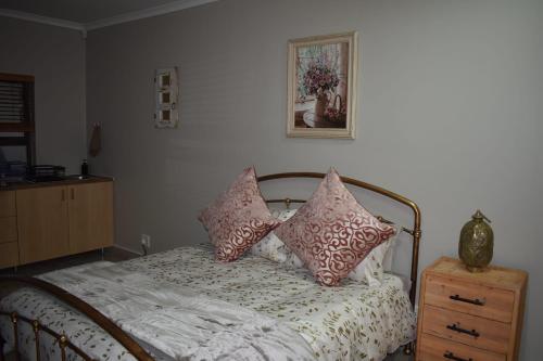 a bedroom with a bed with pillows on it at Pualani Self Catering in Strand