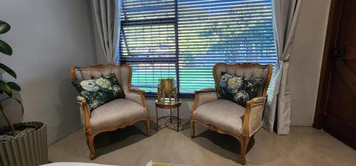 a living room with two chairs and a window at McCrae's Garden Suite in Malmesbury