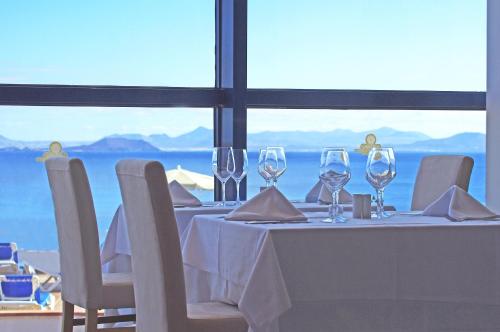a table with wine glasses and chairs with a view at Sandos Papagayo in Playa Blanca