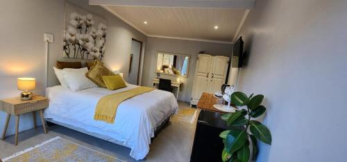 a bedroom with a bed with white sheets and yellow pillows at McCrae's Garden Suite in Malmesbury