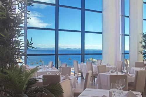a restaurant with white tables and chairs and a large window at Sandos Papagayo in Playa Blanca