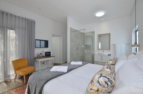 Un dormitorio con una gran cama blanca y una silla. en Caracal 54 Overnight for 2, en Yzerfontein
