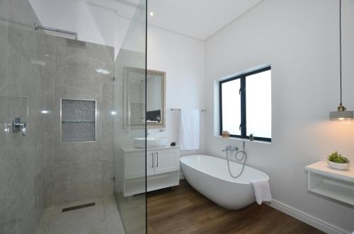 Un baño blanco con bañera y lavabo. en Caracal 54 Overnight for 2, en Yzerfontein